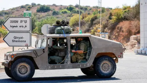 Reuters Israeli soldiers drive a military vehicle near Kiryat Shmona, in northern Israel (9 October 2024)