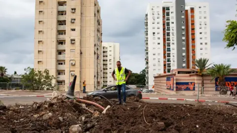 Getty Images Residents and Israeli officials inspect the damage following an overnight rocket attack in Haifa, Israel (7 October 2024)