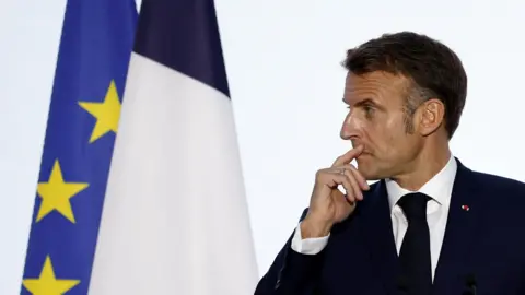 Reuters Macron in profile wears a tie and blazer next to an EU flag at a press conference at the 19th Francophonie Summit at the Grand Palais in Paris