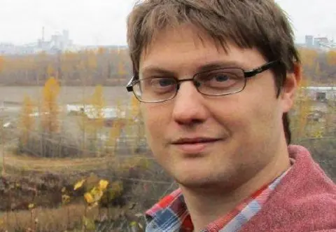 Peter Todd / GITHUB Peter Todd looks at the camera while wearing glasses and a red shirt and standing outside with autumnal trees and a power station in the background