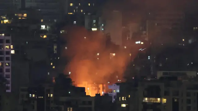 Smoke and fire rise buildings in Beirut at night