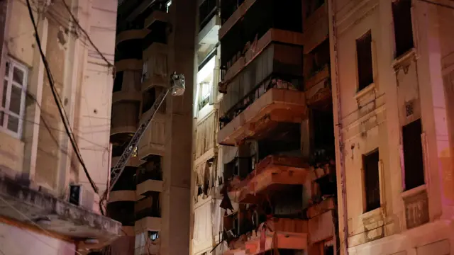 Someone in an extendable lift assesses damage on a building in Beirut