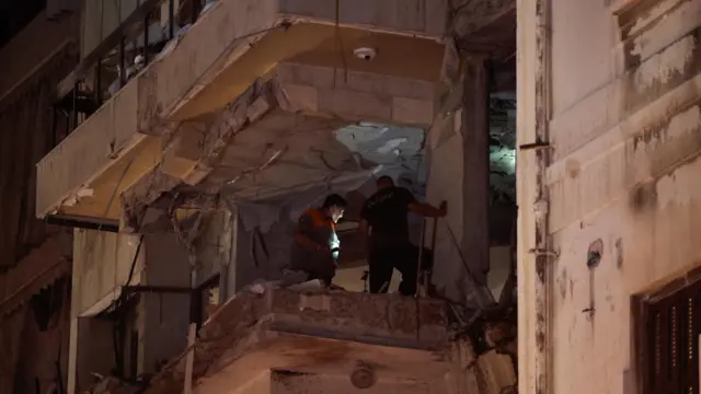 People inspect inside a damaged building at the site of an Israeli air strike