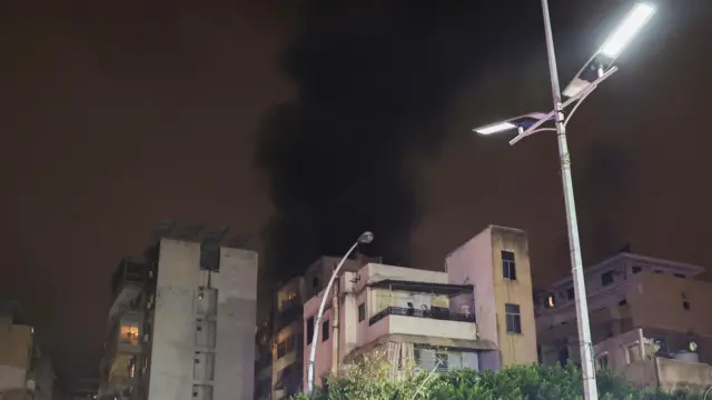 A building stands on the street while smoke raise