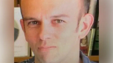 New Zealand Police Tom Phillips pictured with a close up image on his face. He is looking directly at the camera with a neutral expression.