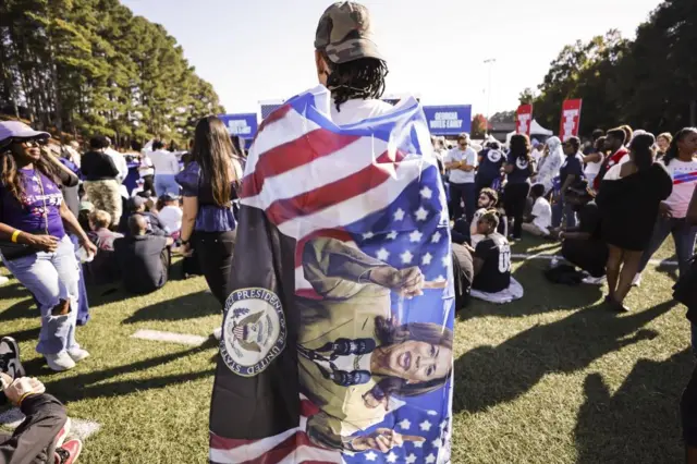 A man draped in a flag depicting US presidential candidate Kamala Harris