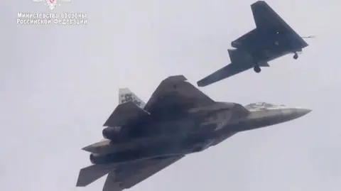 Russian defence ministry This old Russian defence ministry picture shows the Su-57 jet flying in tandem with the Okhotnik combat drone