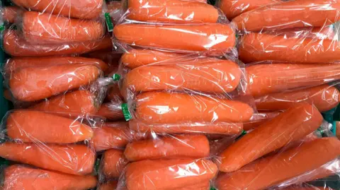 Getty Images Plastic wrapped carrots in a green grocery box. Stock image