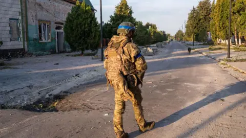 Getty Images A Ukrainian soldier walks through a town in Russia's Kursk region.