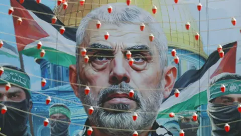 EPA A mural with the face of Yahya Sinwar, the slain former leader of Hamas, beside images of Hamas fighters, with the Palestinian flag and Al-Aqsa mosque in Jerusalem in the background