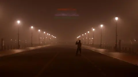 Reuters A man sweeps a road near India Gate as the sky is enveloped with smog after Delhi's air quality turned "severe" due to alarming air pollution, in New Delhi, India, November 18, 2024. REUTERS/Anushree Fadnavis