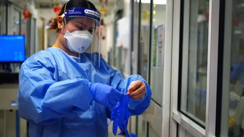 PA An NHS worker wearing personal protective equipment (PPE) including gloves, gown, mask and a face shield