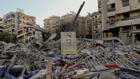 EPA An image of a Hezbollah fighter is displayed on the rubble following an Israeli strike on the suburb.