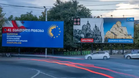 Matthew Goddard/BBC A billboard in Tbilisi compares the war in Ukraine to the peace in Georgia