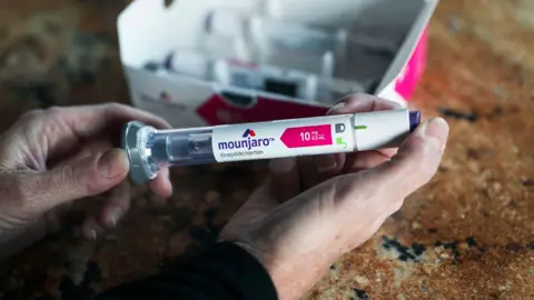 The Washington Post via Getty Images A close up of a persons hands holding the packaging for a Mounjaro injection, taken in California in 2023.