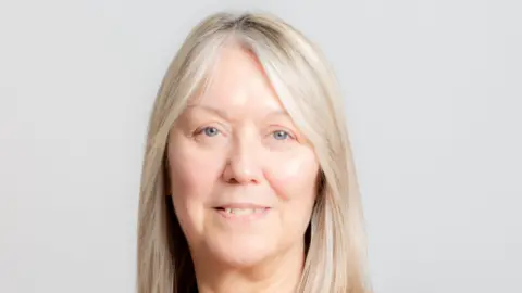 Alison Spooner Portrait of Alison smiling straight to camera with blond hair and blue eyes.