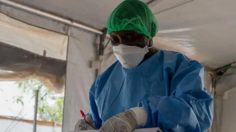 AFP An image of a doctor wearing a white face mask and a blue medical apron.