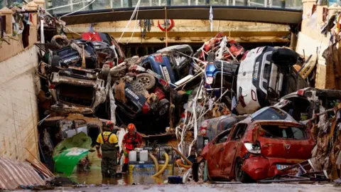 Reuters Firefighters pump out the floodwater out of a tunnel in Valencia. Cars block up the entrance of the tunnel.