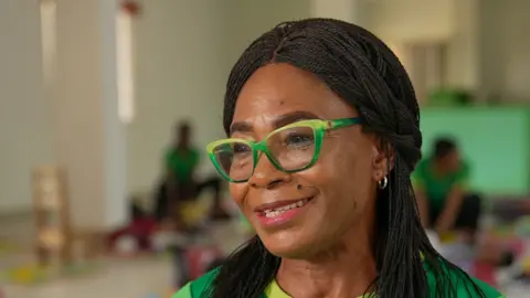 Joyce Liu / BBC A close-up photo of Nonye Nweke wearing green glasses. She has long hair.