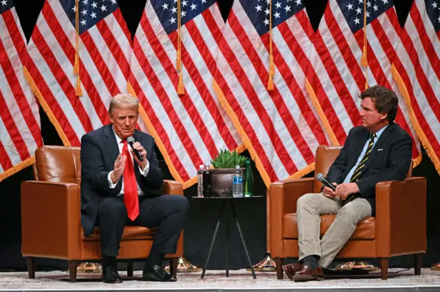 Former US President and Republican presidential candidate Donald Trump (L) speaks during a live interview with US commentator Tucker Carlson (R)