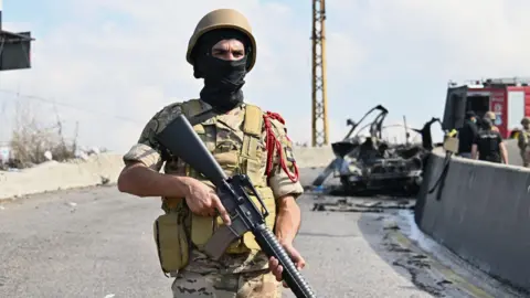 EPA A Lebanese soldier stands in front of the wreckage of a car