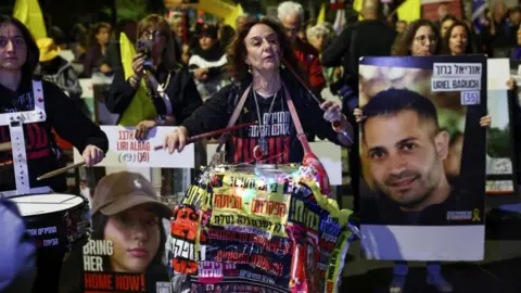 Reuters A woman beats a drum as she marches with others who hold flags and placards bearing the faces of hostages