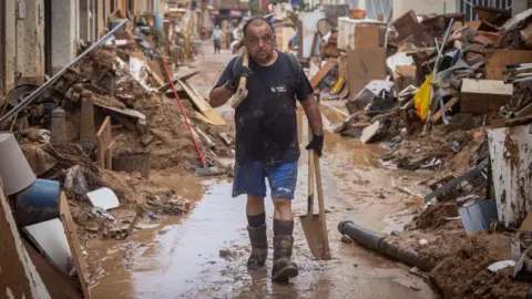 Getty Images A man cleans his house after heavy rain and flooding hit large parts of the country on 4 November, 2024 in Paiporta, Spain.