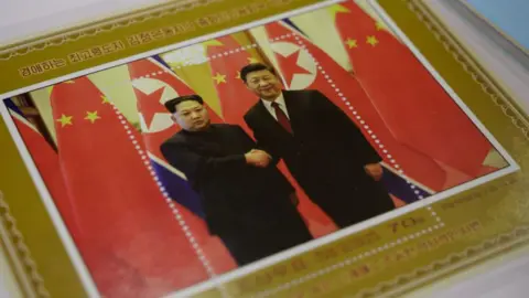 AFP A commemorative stamp featuring North Korean leader Kim Jong Un (L) meeting with China's leader Xi Jinping is pictured at a shop in Pyongyang on June 18, 2019