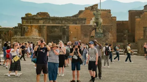 Getty Images Tourists crowd the the Archaeological Park of Pompeii, walking around and taking pictures.