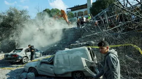 Reuters young men are seen near damaged cars at the site of an Israeli air strike near Byblos